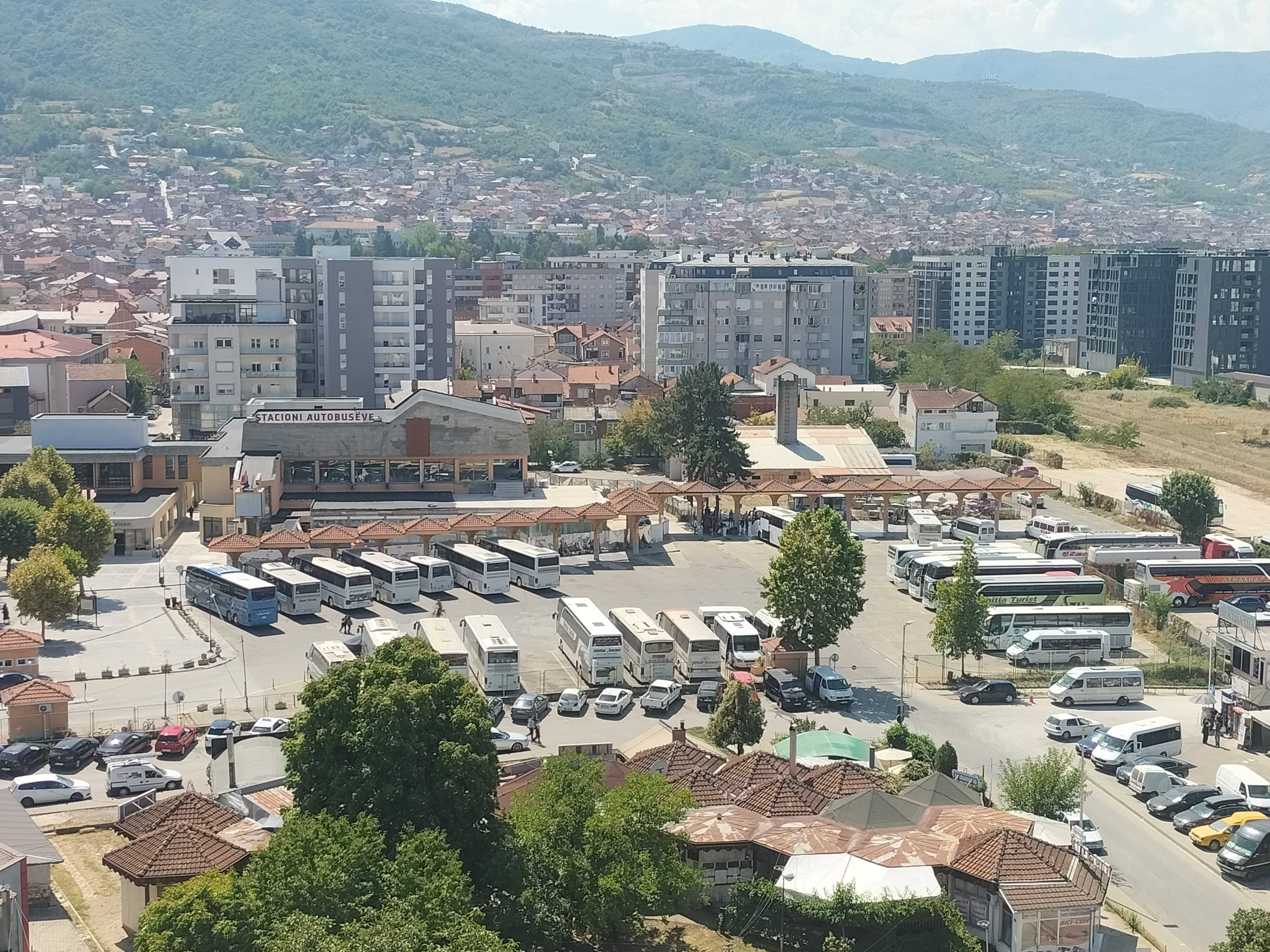 Main Bus Station in Prizren (Призрен) from above. In the background the main building can be seen. In the foreground many busses from different companies are lined up.